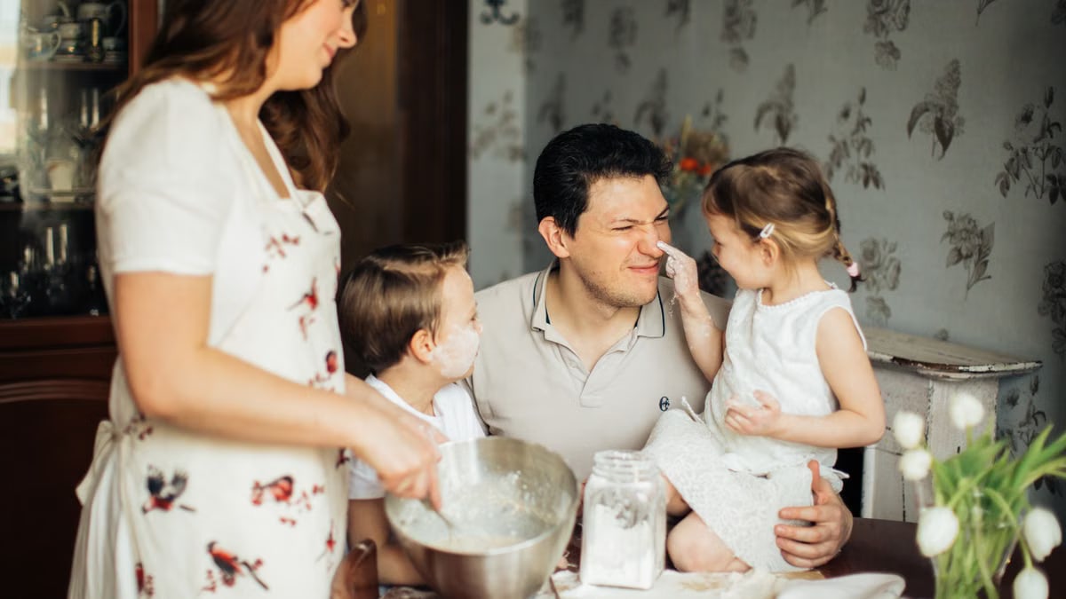 A joyful family moment with parents and children baking together in the kitchen.